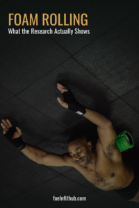 Man doing foam rolling recovery on the gym floor after a workout